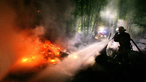 Ein Feuerwehrmann löscht einen Waldbrand. (Symbolbild)