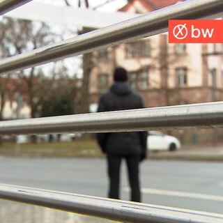 Ein Polizeibeamter steht an einer Straße, den Blick auf ein Amtsgericht und ein Gefängnis gerichtet.