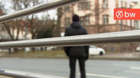 Ein Polizeibeamter steht an einer Straße, den Blick auf ein Amtsgericht und ein Gefängnis gerichtet.