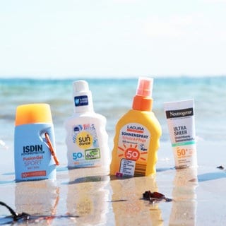 Sonnencremes, die im Sand am Strand stehen