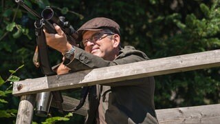 Bernhard mit angelegtem Gewehr auf dem Hochsitz