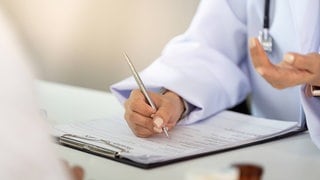Ein Ärztin macht sich während eines Patientengesprächs in einer modernen Gesundheitseinrichtung Notizen.