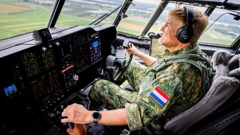 König Willem-Alexander sitzt in einem Militärflugeug im Cockpit und steuert es.