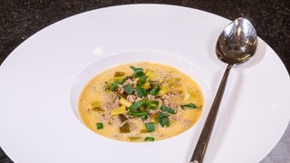 Die fertige Lauch-Hackfleisch-Suppe in einem weißen Suppenteller mit einem Löffel an der Seite.