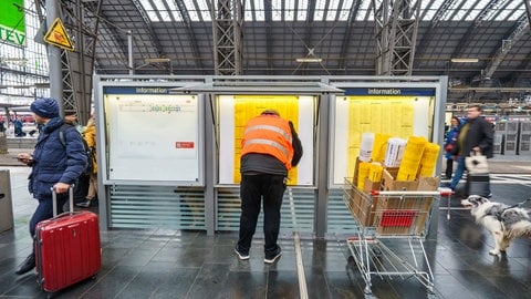 Ein Mitarbeiter hängt neue Fahrpläne in die Infokästen. Am 14. Dezember 2025 ist Fahrplanwechsel bei der Deutschen Bahn.