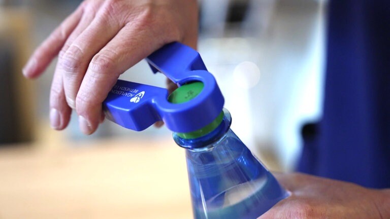 Hand hält eine blaue Kunststoffzange an Deckel einer Plastikflasche. Apptitlosikeit und Gewichtsverlust im Alter, was tun?