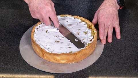 Nun kommt die Haube aus Baiser: Die Masse aus Zucker und Eischnee wird auf den Rhabarberkuchen gestrichen.