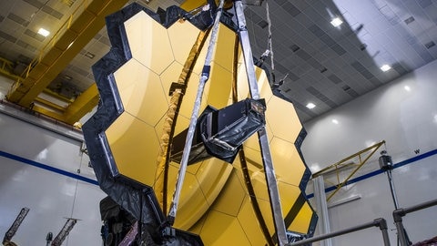James-Webb-Weltraumteleskop nach einem erfolgreichen Entfaltungstest seines Hauptspiegels in der gleichen Konfiguration, die es im Weltraum haben wird. Die Weltraumbehörden Europas, der USA und Kanadas wollen mit dem neuen Teleskop mehr über das frühe Universum lernen. Mit dem Teleskop sollen die ersten nach dem Urknall entstandenen Galaxien beobachtet werden.