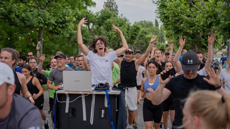 Der DJ Mika Hohlbaum am mobilen Mischpult umgeben von zahlreichen Joggern beim ersten "Run and Rave" in Konstanz