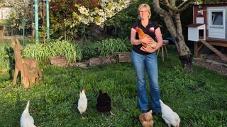 Simone Metzger ist mit ihren Hühnern, die sie bei sich aufgenommen hat, im Garten.