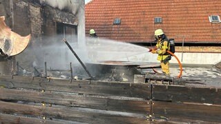 Ein Feuerwehrmann löscht am 5.6.2025 eine Dachterrasse in der Altstadt von Speyer