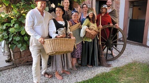 Auf Zeitreise geht's heute Nachmittag in Clausen in der Südwestpfalz: Da führen verkleidete Schauspieler durch den Ort, um Anmeldung wird gebeten. (Menschen stehen mittelalterlich verkleidet zusammen.)