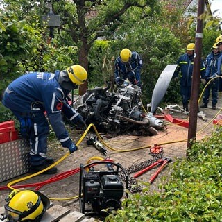 Einsatzkräfte schneiden den Motor des abgestürzten Kleinflugzeugs in zwei Teile, um ihn besser abtransportieren zu können.