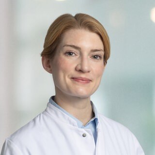 Transgender-Chirurgin Isabella Kurth steht in weißem Arztkittel da.