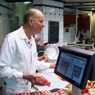 Bernd Glasstetter steht hinter der Fleischtheke seiner Metzgerei in Völkersbach und bedient Kundschaft.