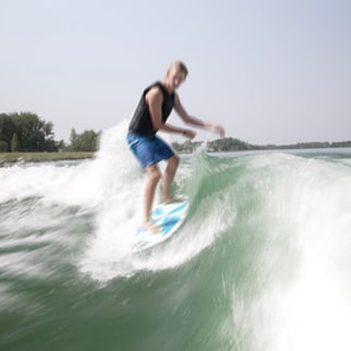 Wakesurfer Meo Stirm surft auf den Wellen des Rheins und balanciert auf seinem Board.