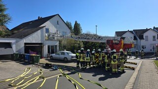 Die Feuerwehr steht vor einem Einfamilienhaus in Simmern im Hunsrück. Bei dem Brand des Hauses ist die Bewohnerin verstorben, laut Polizei vermutlich an einer Rauchgasvergiftung.