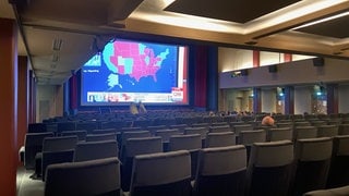 Menschen sitzen im Kinosaal in Tübingen und schauen sich die Live-Übertragung des Senders CNN zur Wahl in den USA an.