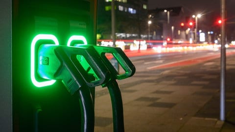 An einer Schnellladesäule für E-Autos leuchten Ladekabel grün.