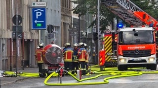 Einsatzkräfte der Feuerwehr stehen vor einem Parkhaus in der Karlsruher Innenstadt. Wegen eines Brandes in dem Parkhaus kam es zu einem größeren Einsatz von Polizei und Feuerwehr.