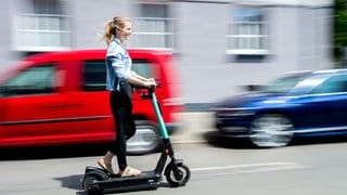 Eine Frau fährt mit einem E-Scooter auf der Straße.