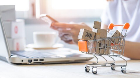 Shopping cart with Paper box or parcel with blur background woman holding mobile phone. Businesswoman or entrepreneur working from home. Online shopping, e-commerce,internet banking, spending money.