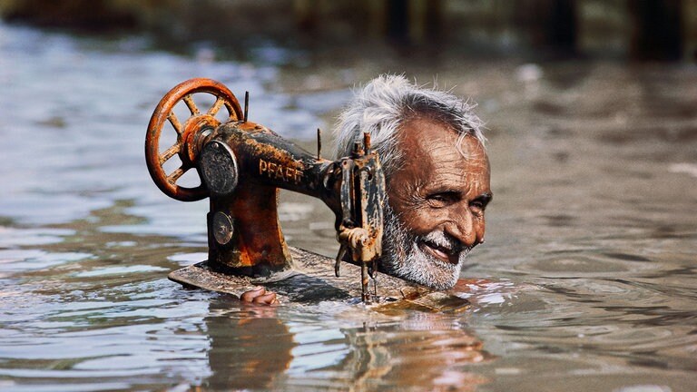 Ein Schneider trägt seine Nähmaschine durch das Monsunwasser, Porbandar, Gujarat, 1983