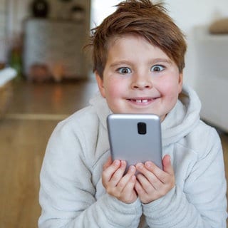 Beispielbild für: Eine Junge freut sich über sein erstes Smartphone.