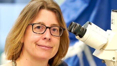 Die Heidelberger Infektionsmedizinerin Claudia Denkinger neben einem Mikroskop