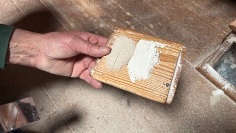 Rainer Mosen zeigt unterschiedliche Mehlsorten auf einem kleinen Stück Holz.