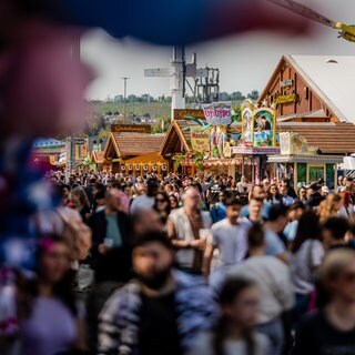 Besucher strömen bei schönem Wetter über das 85. Stuttgarter Frühlingsfest.