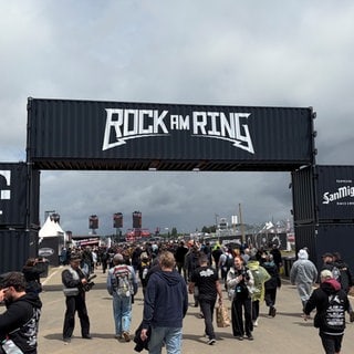 Besucher laufen auf das Festivalgelände bei Rock am Ring
