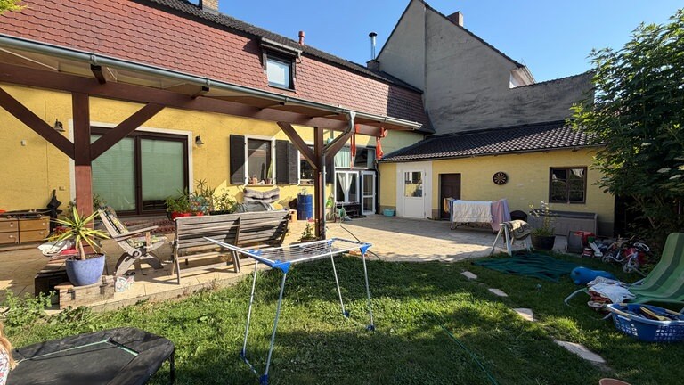 Das ehemalige Bauernhaus auf dem Gelände des Wohnprojektes Feldwinkel. Es gibt eine Gemeinschaftsterasse. Im Garten davor trocknet Wäsche.