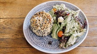 Mit Sesam panierter Ziegenweichkäse und Salat auf einem Teller