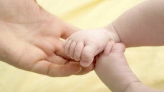 Eine Hand hält Babyfüße.