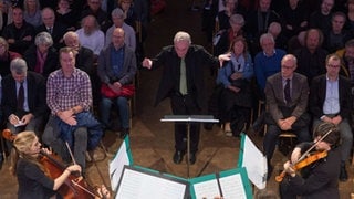 Mann dirigiert Musiker*innen