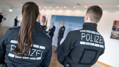 Zwei Polizeibeamten, die neue Uniformen anhaben, verfolgen während eines Pressetermin eine Pressekonferenz. Die baden-württembergische Polizei bekommt neue Uniformen, die mit "schnitthemmenden Elementen" versehen sind.