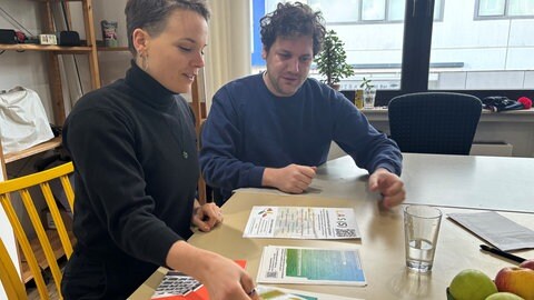 Anni und Christian schauen auf Unterlagen. Die beiden wollen mit dem Verein "KOlibri" ein solidarisches Wohnprojekt in Koblenz umsetzen. 