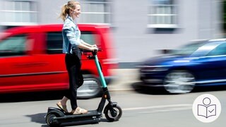Eine junge Frau fährt mit einem E-Scooter auf der Straße. Im Hintergrund ist ein rotes Auto. Rechts das SWR Logo für Leichte Sprache.  