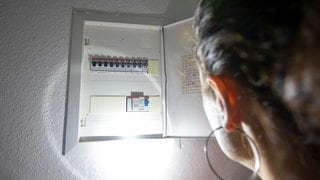 Eine Frau leuchtet mit einer Taschenlampe in einen Sicherungskasten - In RLP gilt bei einem Blackout Eigenvorsorge