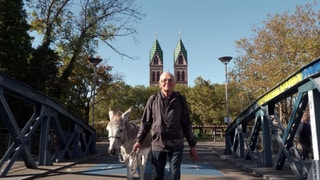 Ernst König geht mit Esel Charly in Freiburg über eine Brücke