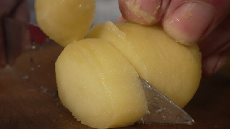 Damit die Kartoffelscheiben nicht aneinander kleben, empfiehlt es sich, das Messer zwischendurch unter Wasser zu halten.