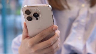 Eine Frau hält ein weißes iPhone in der Hand | 50 Jahre Apple: Vom iPhone zur KI?