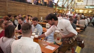 Ein Wasenkellner auf dem Cannstatter Wasen. Er bedient gerade einen Tisch.