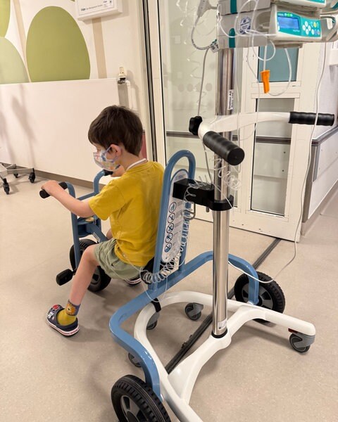 Ein Junge fährt mit einem speziellen Fahrrad über den Flur der Kinderkrebsstation in Mainz. An dem Rad kann ein Infusionsständer angebracht werden