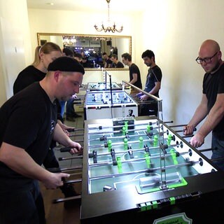 Timo Zipper spielt mit drei Personen Tischkicker.