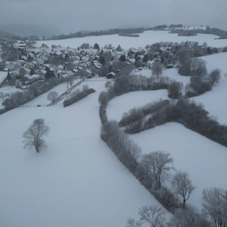 Luftaufnahme des verschneiten Orts Ochsenwang mit winterlicher Landschaft auf der Schwäbischen Alb.