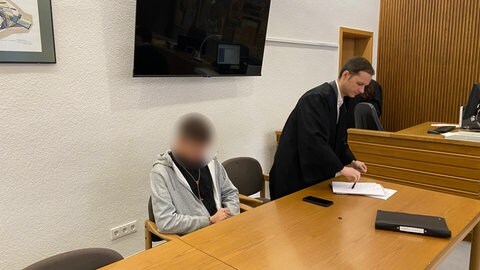 Ein Mann sitzt auf der Anklagebank. Sein Verteidiger daneben