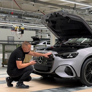 Ein Mercedes-Mitarbeiter prüft in einem Werk die Qualität eines Autos
