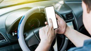 Symbolfoto: Eine Person bedient das Smartphone während der Fahrt | Mit der Aktionswoche "Lenken statt liken - Fahr sicher ohne Handy!" macht SWR1 die Straßen sicherer. Gemeinsam mit dem ADAC klären wir auf und verlosen Fahrsicherheitstrainings.